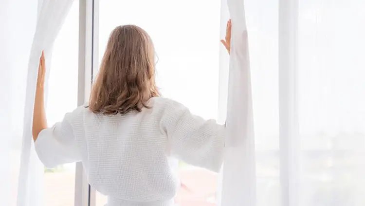 Γυναίκα απολαμβάνει καθαρό και υγιεινό αέρα στο σπίτι της χάρη στα συστήματα εξαερισμού ανάκτησης ενέργειας STIEBEL ELTRON.