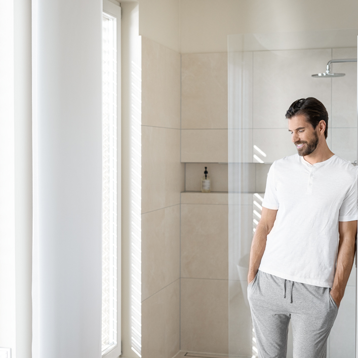 Άνδρας στο μπάνιο δίπλα στο ντους — άμεσο ζεστό νερό χωρίς αναμονή με STIEBEL ELTRON